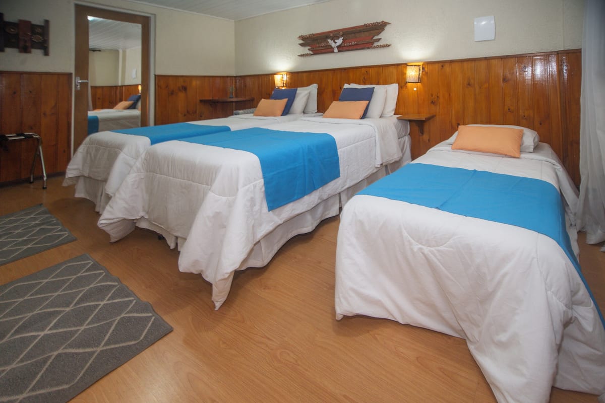 Une chambre d’hôtel avec deux lits, des panneaux en bois au niveau de la tête de lit et un miroir au mur.