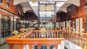 A spacious atrium with a central wooden staircase, flanked by glass railings and potted plants. - Guida Residenza Pousada (Campos do Jordão)