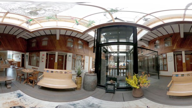 A spacious atrium with a central glass elevator, wooden benches, and potted plants. - Guida Residenza Pousada (Campos do Jordão)