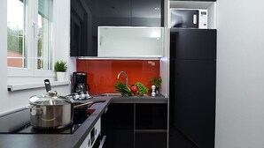 A modern kitchen with a black and white color scheme, a built-in oven, a coffee maker, and a window with a view of the outside. - Villa Adria II, apartment B3, with 2 swimming pools (Pag)