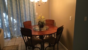 Un coin repas avec une table ronde, quatre chaises, un lustre et une plante en pot.