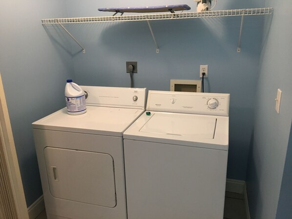 A laundry area with two white washing machines, a drying rack, and a bottle of detergent. - One Bedroom Condo in the heart of Biloxi (Biloxi)