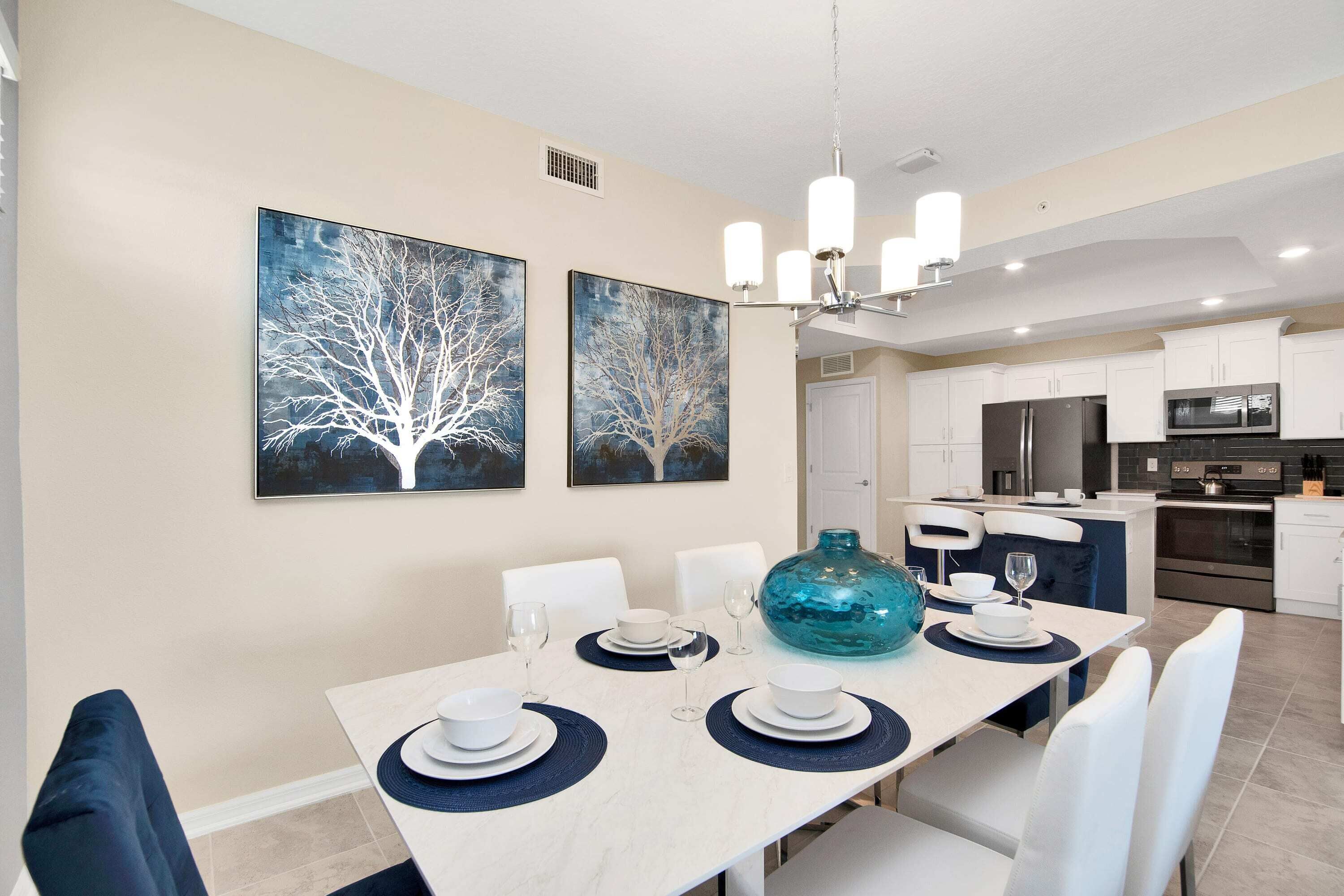 A dining area with a table set for four, white chairs, and a large blue vase.