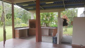 An outdoor patio with a brick barbecue area, a hanging hammock, and a trash bin.