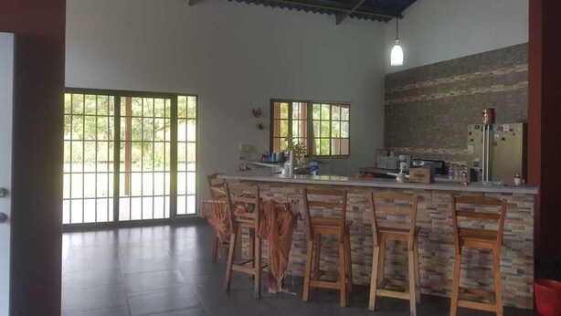 A kitchen with a bar area, large windows, and a stone backsplash.