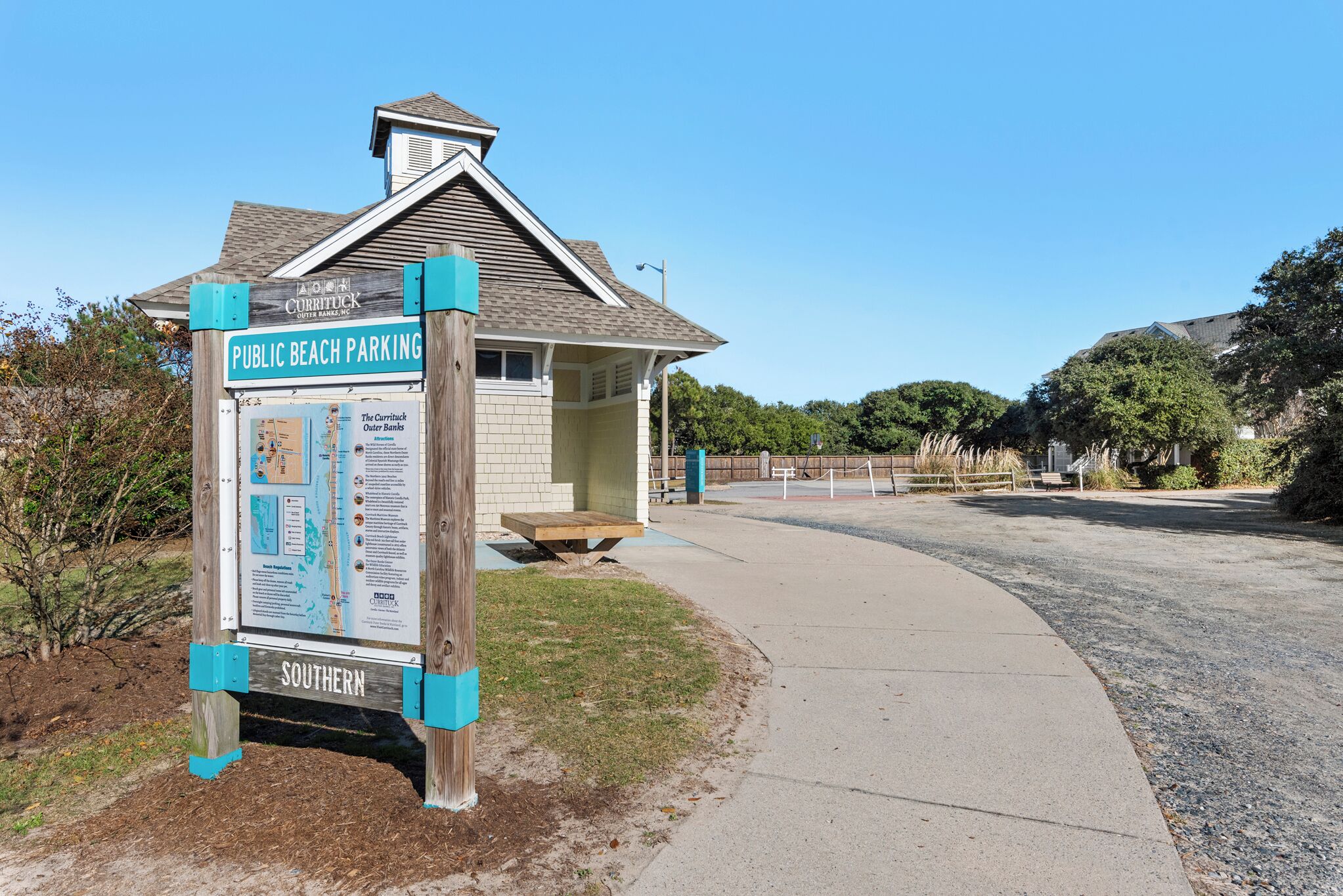 A wooden signboard for public beach parking with a map and information.