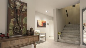 Un interior moderno con una consola de madera, un cuadro abstracto grande, una silla y una escalera.