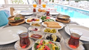 Desayuno junto a una piscina con diferentes platos, bebidas y vistas al área de la piscina.