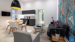 A modern living room with a dining area, a kitchen, and a large window. - Frida Loft (Syracuse)