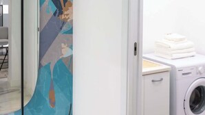 A laundry room with a washing machine and stacked towels. - Frida Loft (Syracuse)