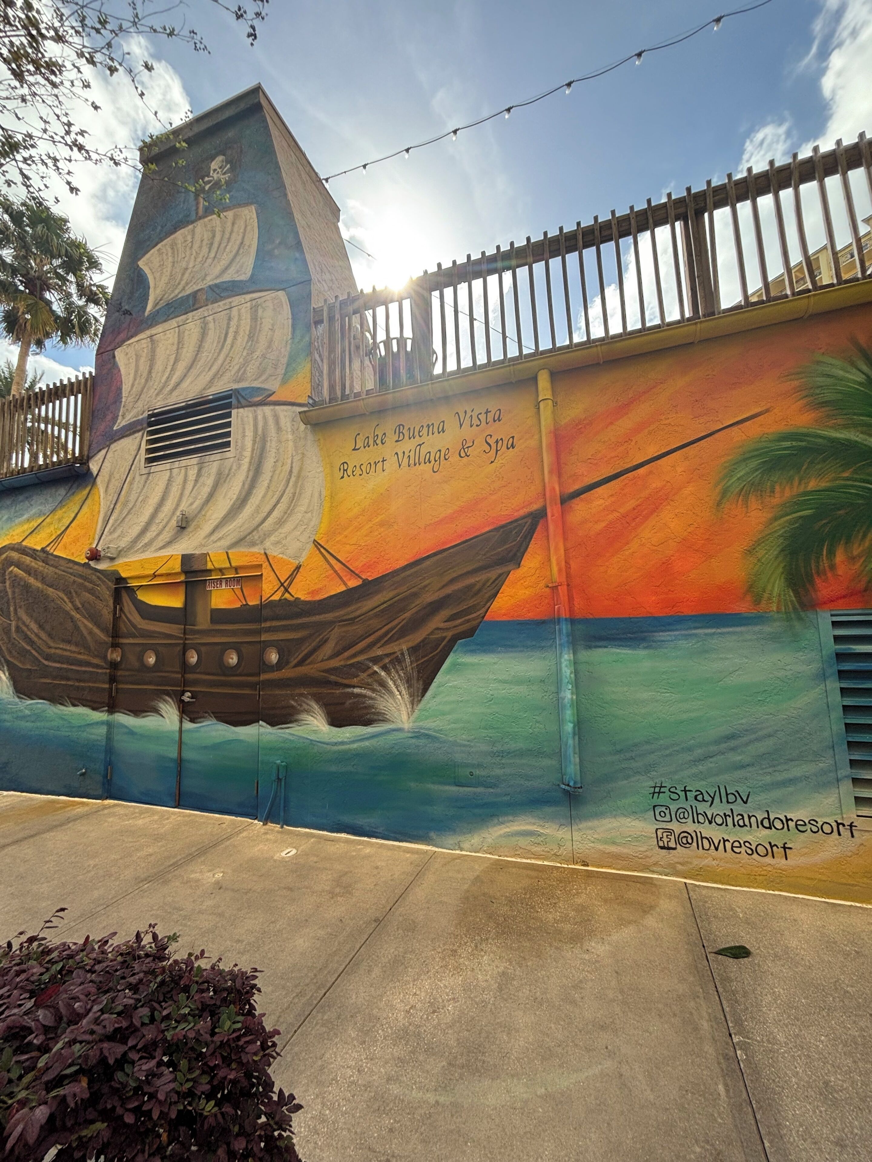 Une fresque représentant un voilier orne le mur d’un bâtiment sur lequel on peut lire l’enseigne « Lake Buena Vista Resort Village & Spa ».