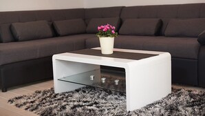 A modern living room with a white coffee table, a potted plant, and a dark grey sectional sofa.