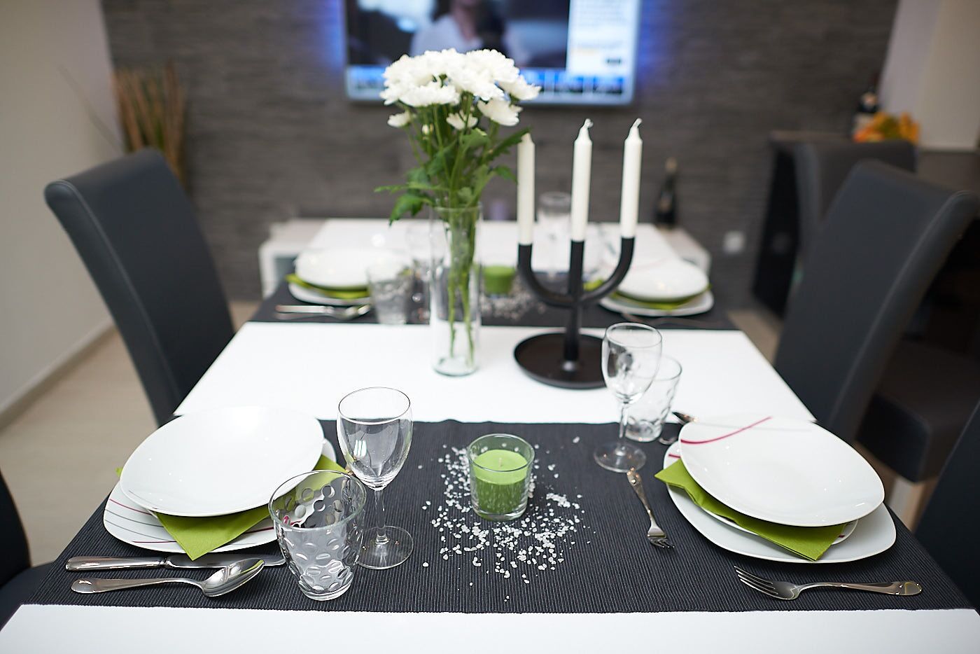 A dining table set with plates, glasses, and a candle holder.