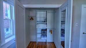 Un dressing accessible sans porte, doté d’étagères, d’une tringle pour suspendre les vêtements et de tiroirs de rangement.