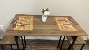 Un tavolo in legno rettangolare dal design vintage, con un vaso bianco e piante verdi al centro.
