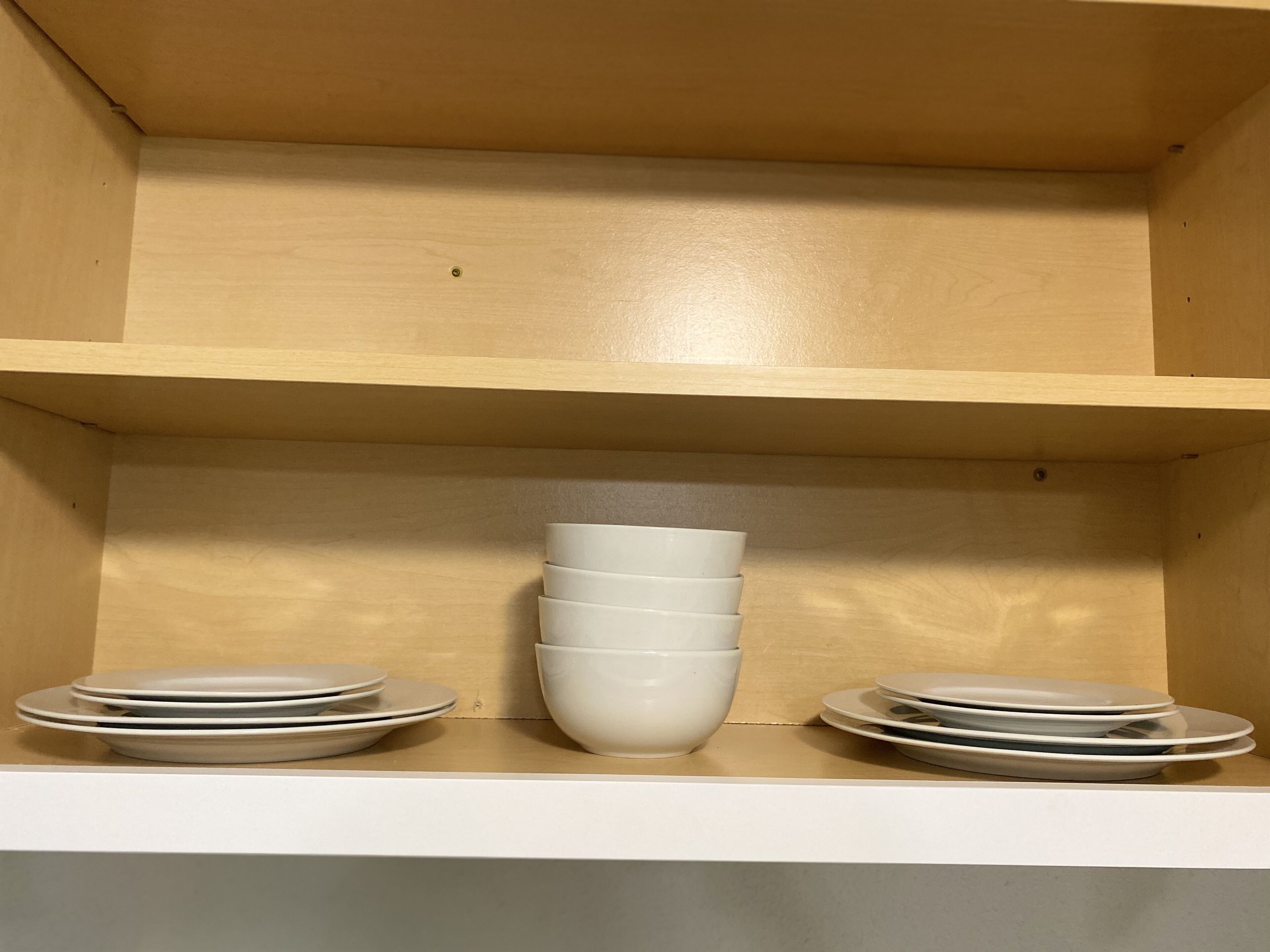 Una estantería de madera con platos y tazones apilados.