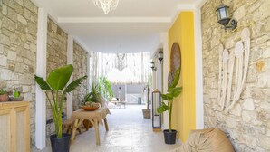 Un interior acogedor con una pared de piedra, una pared de acento amarilla, una zona de comedor con mesa y sillas, y un espacio de descanso cómodo con sofá y una lámpara.