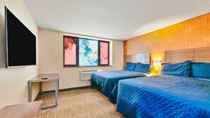 Hotelkamer met twee bedden, een flatscreen-tv, een tafeltje en een raam met abstracte kunst.