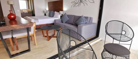 A modern living room with a sofa, two black wire chairs, a wooden dining table, and a coffee table.