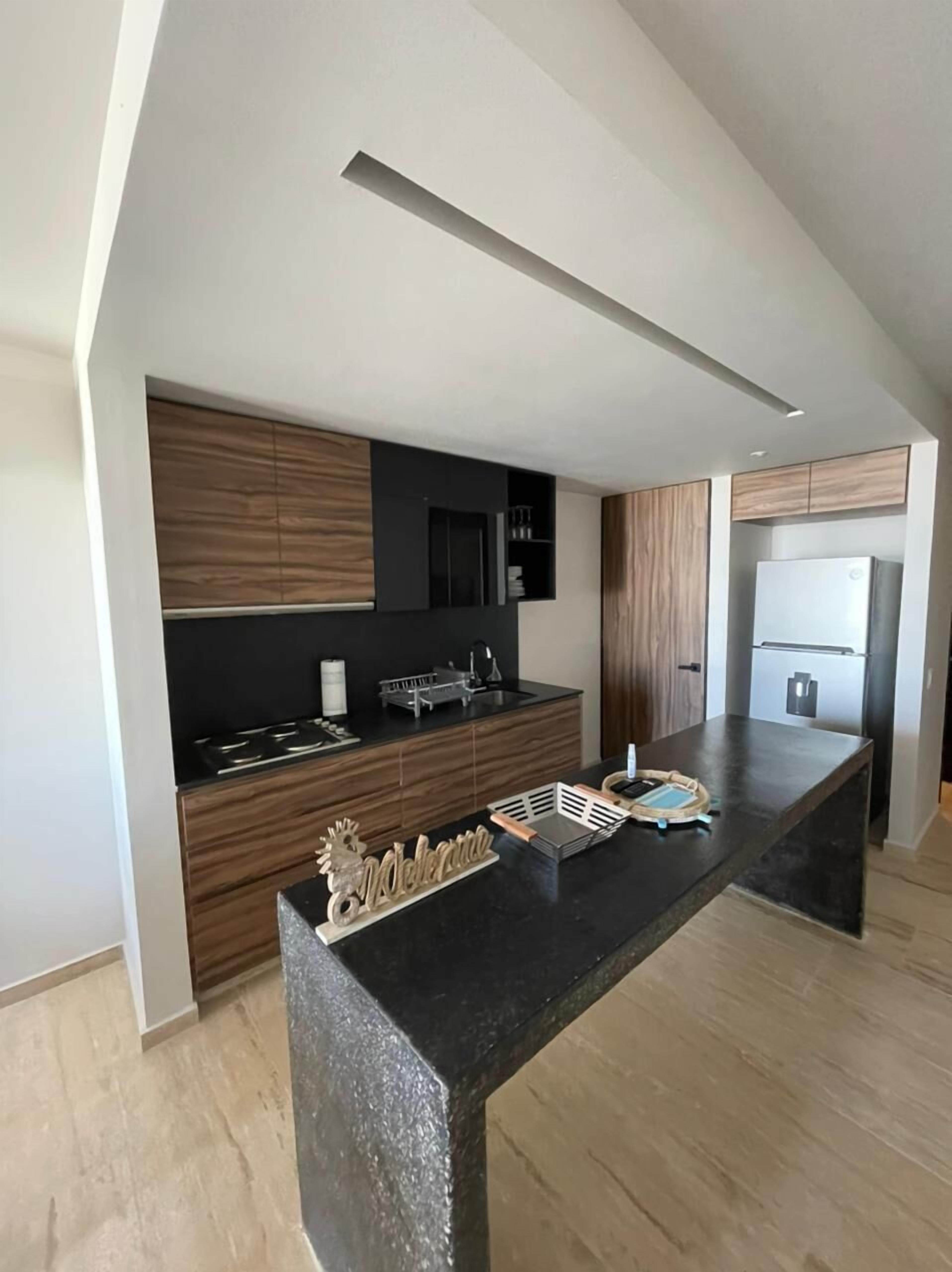 A modern kitchen with a central island, wooden cabinets, and built-in appliances.