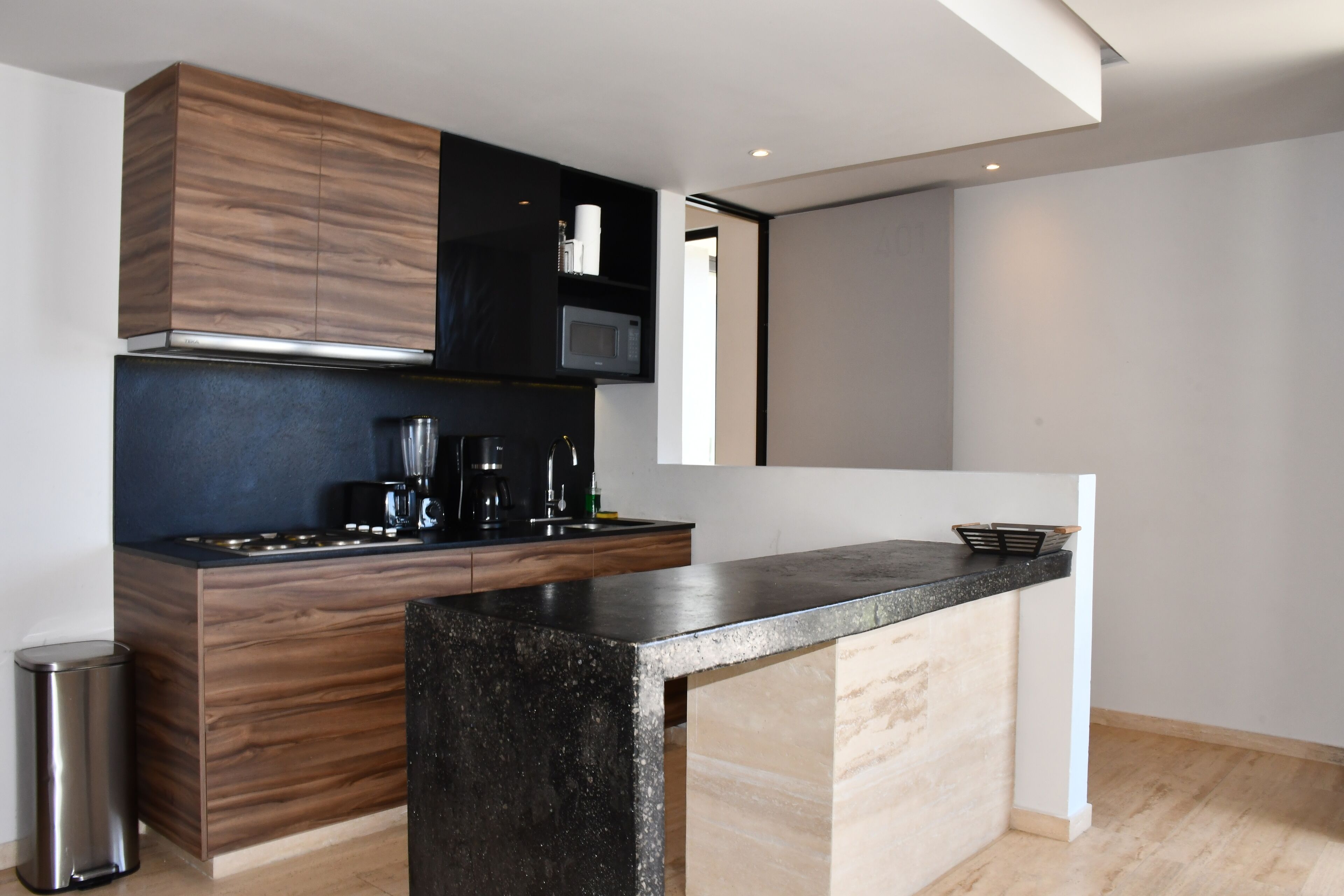 A modern kitchen with a wooden cabinet, a microwave, and a coffee maker.