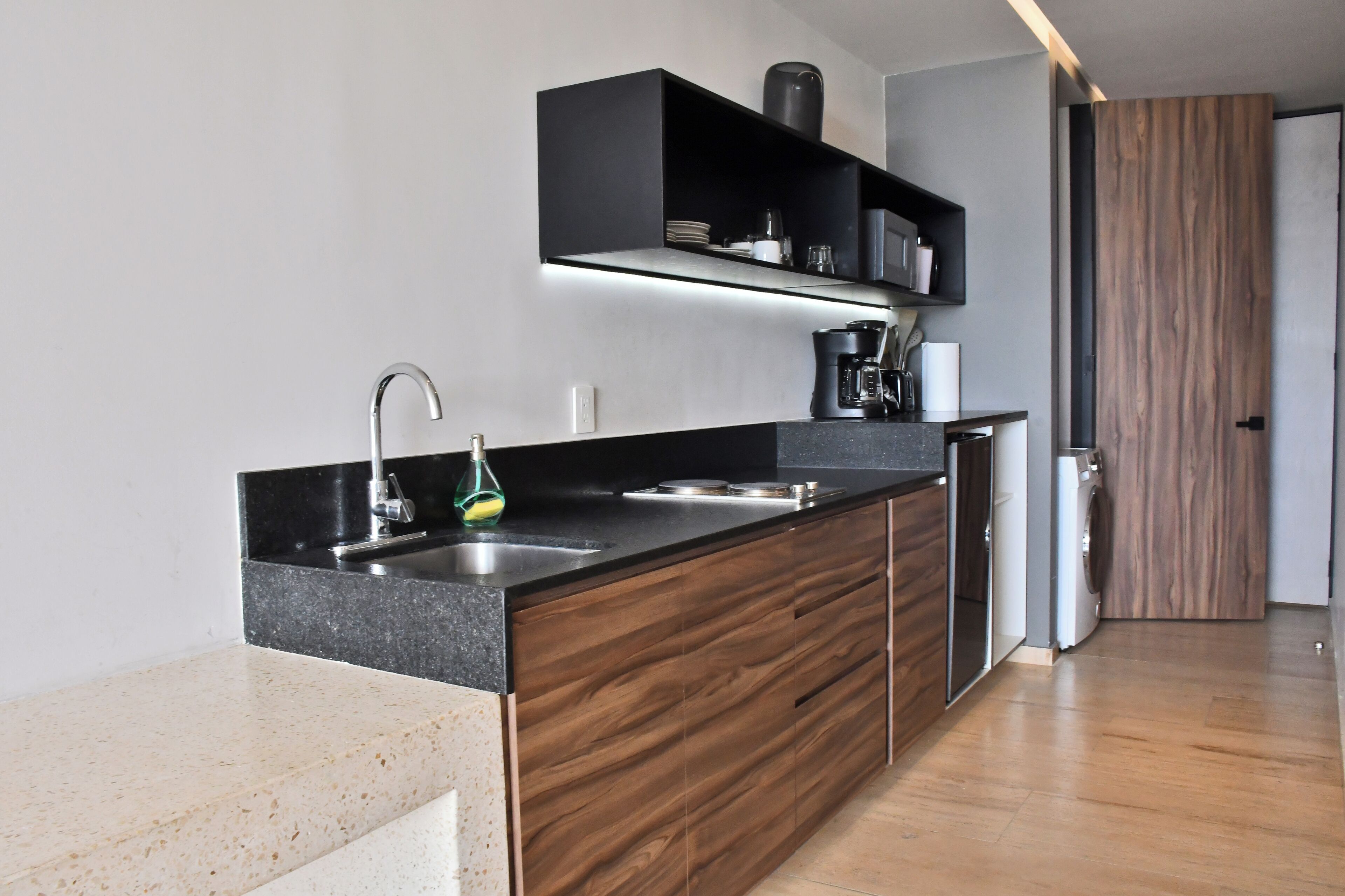 Une cuisine moderne avec un plan de travail noir, des meubles en bois et des appareils électroménagers intégrés.