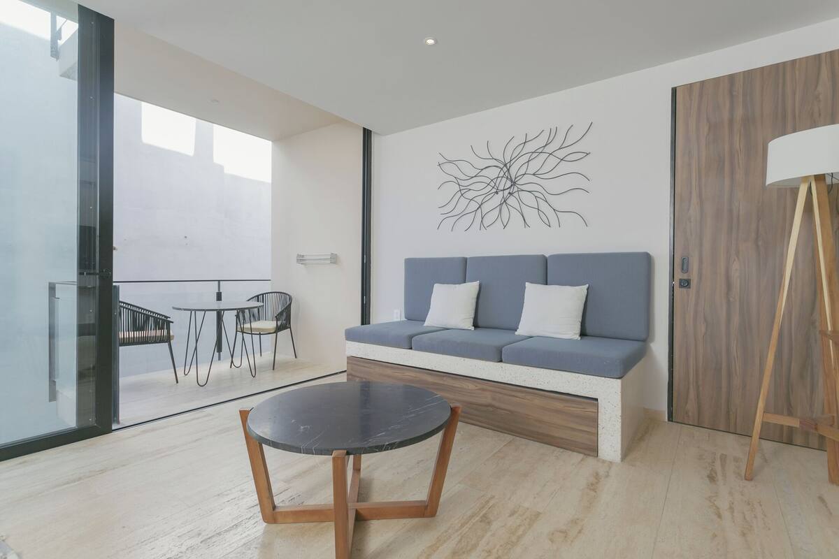 Un salon moderne avec un canapé, une table ronde et une œuvre d’art murale.