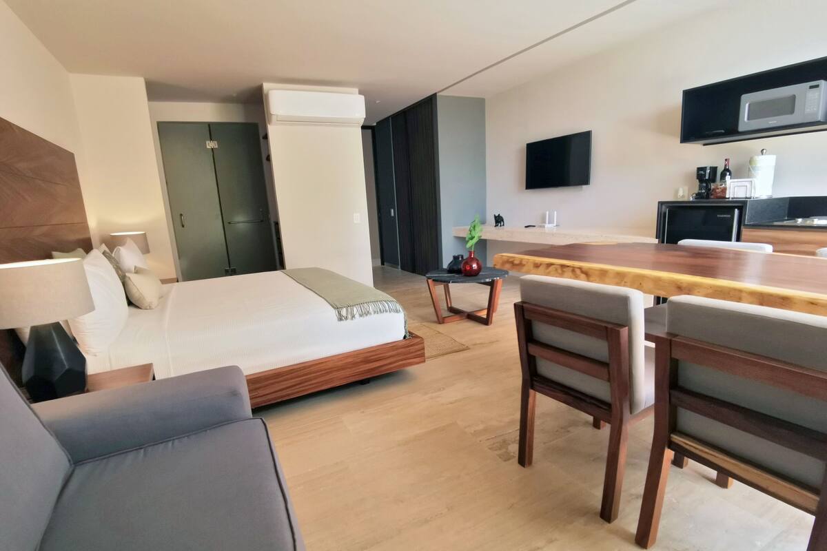 Une chambre d’hôtel moderne équipée d’un lit, d’un bureau, d’une chaise, d’une télévision et d’un four à micro-ondes.