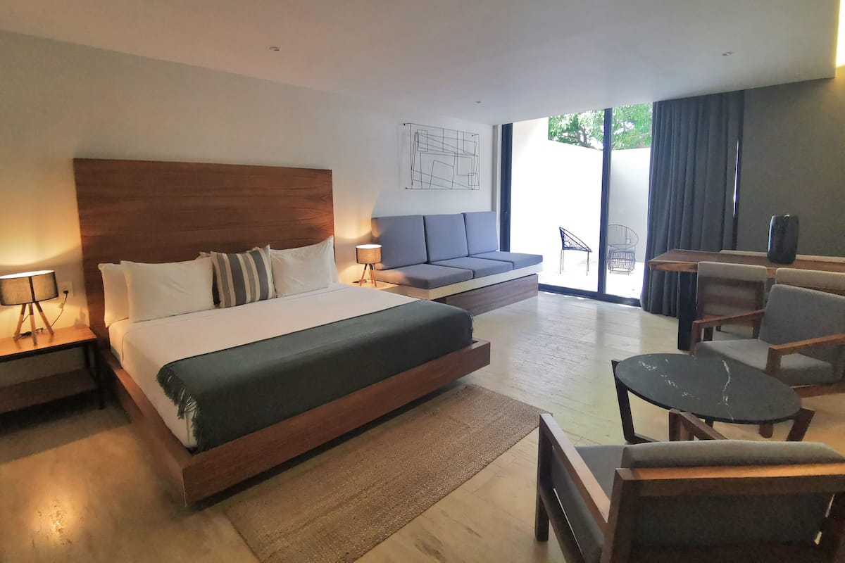 Une chambre d’hôtel moderne avec un grand lit, un canapé, une table à manger et une chaise.