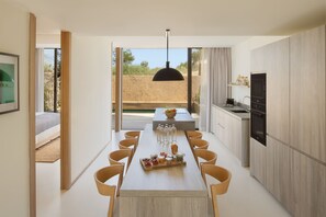 A modern kitchen with a central island, wooden chairs, and a dining table.