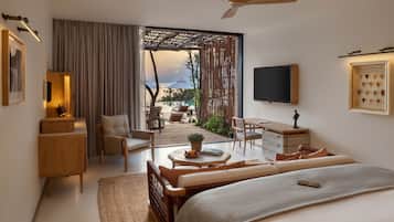 Una habitación de hotel moderna con una cama grande, un escritorio, una silla y un balcón con mobiliario exterior.