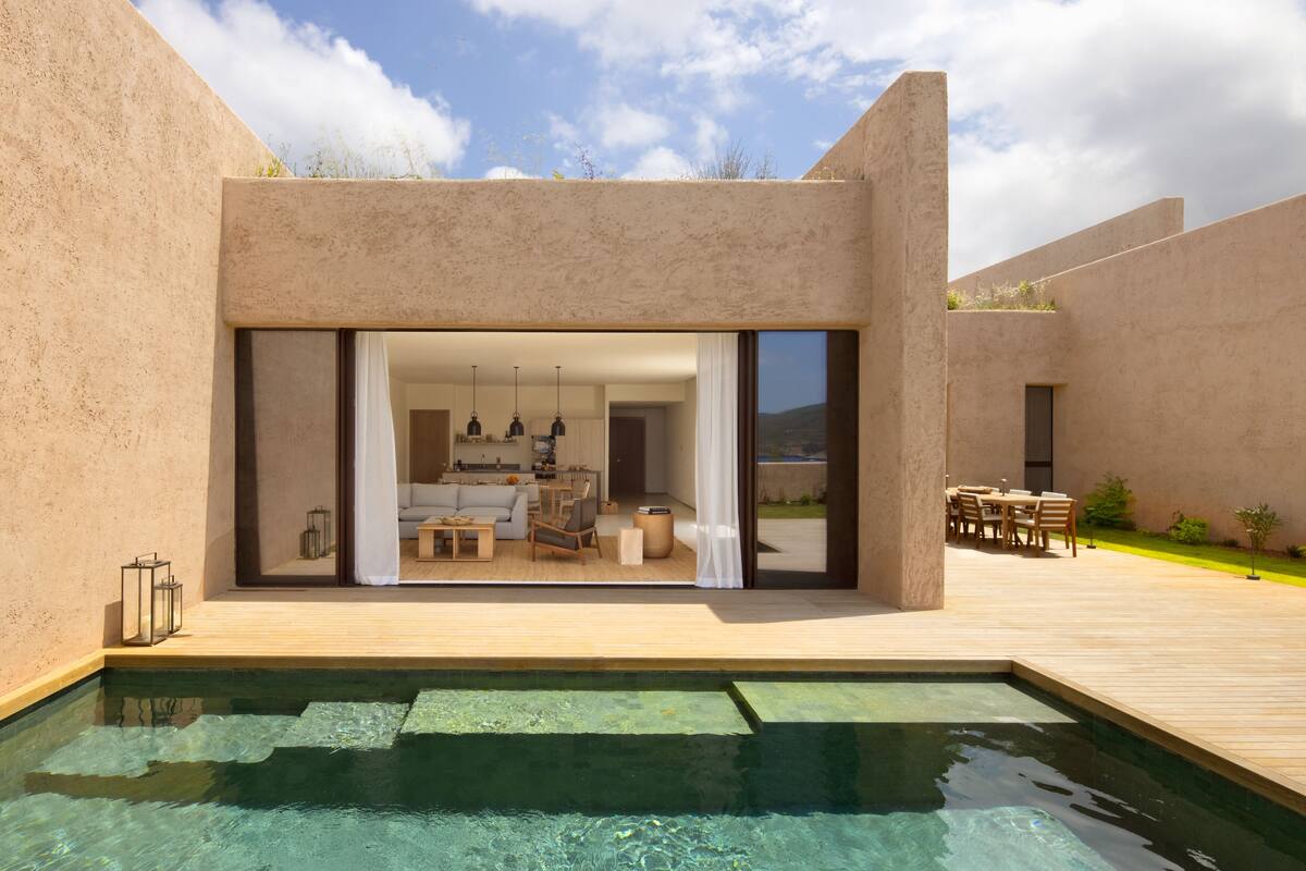 Een modern huis met een zwembad, een terras en uitzicht op het interieur.