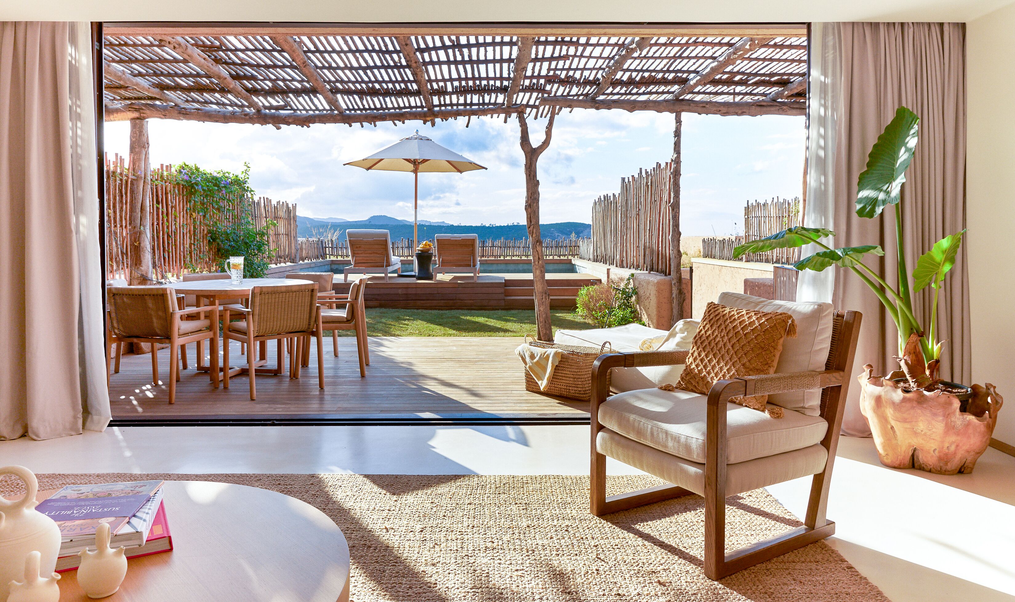 An outdoor patio with a wooden deck, wicker furniture, and a view of the mountains.