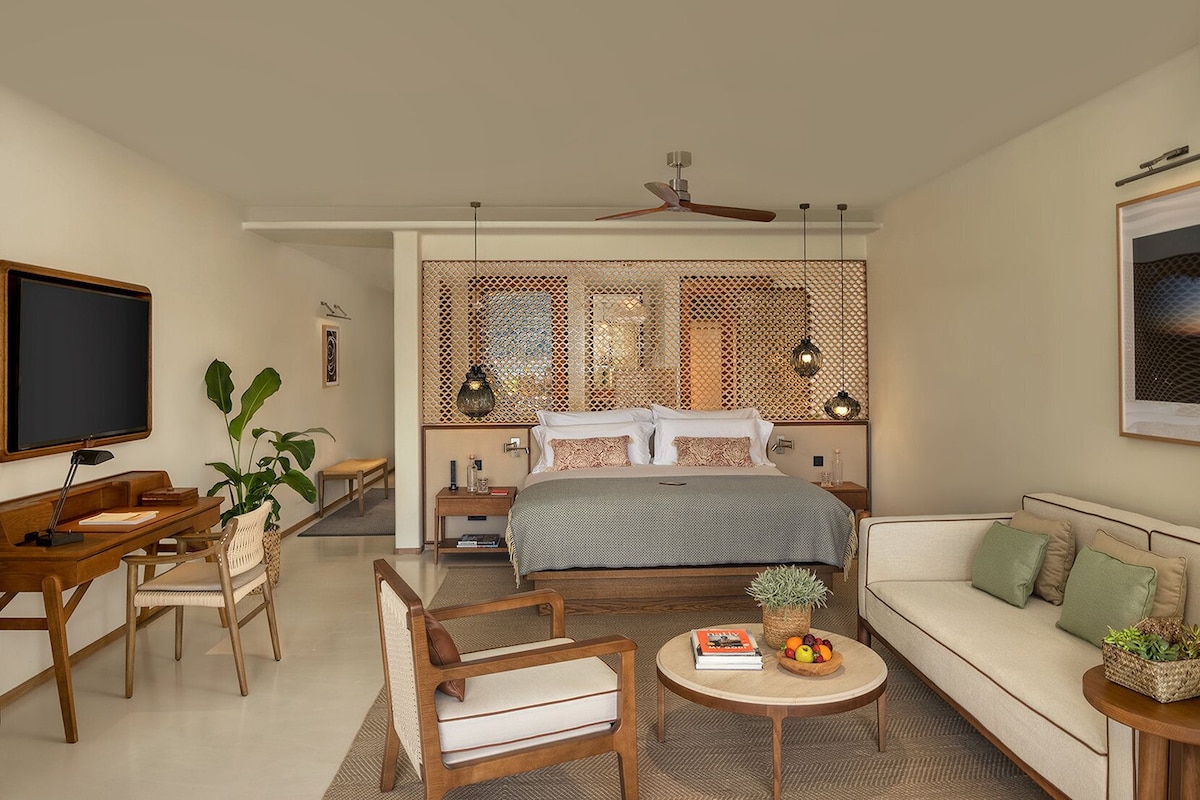 A modern bedroom with a bed, desk, and seating area.