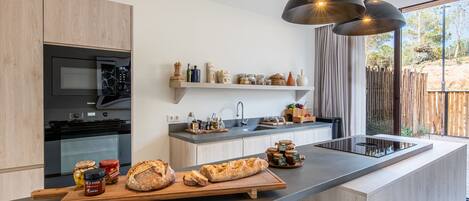 A modern kitchen with a central island, built-in appliances, and a large window providing a view of the outdoors.