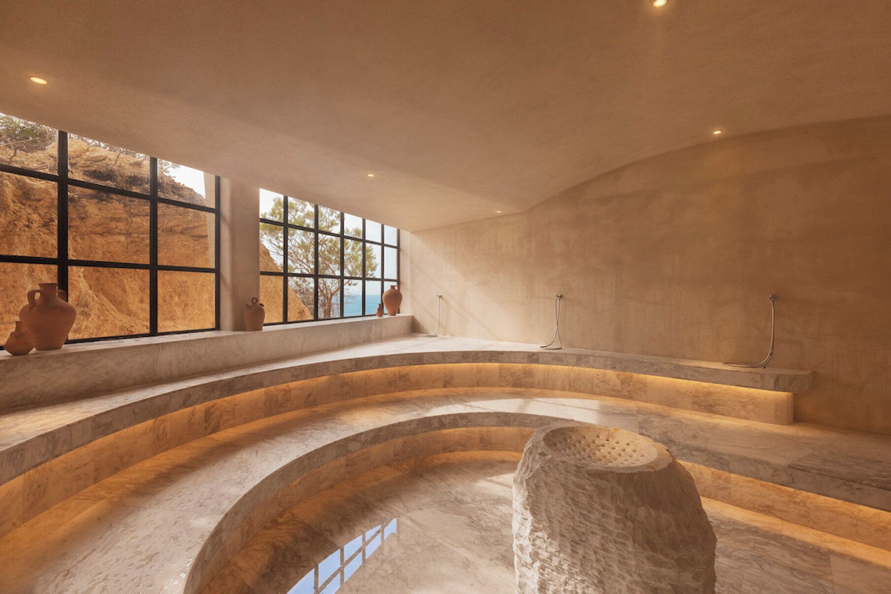 A spacious interior with a large window, a stone structure in the center, and a curved seating area.