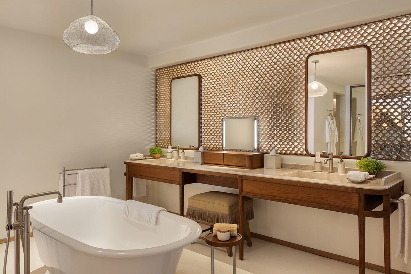 Ein modernes Badezimmer mit freitstehender Badewanne, einem Doppelwaschbecken mit Spiegeln und einer dekorativen Wandverkleidung.