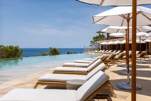 Una piscina al aire libre, sombrillas, sillones reclinables de piscina