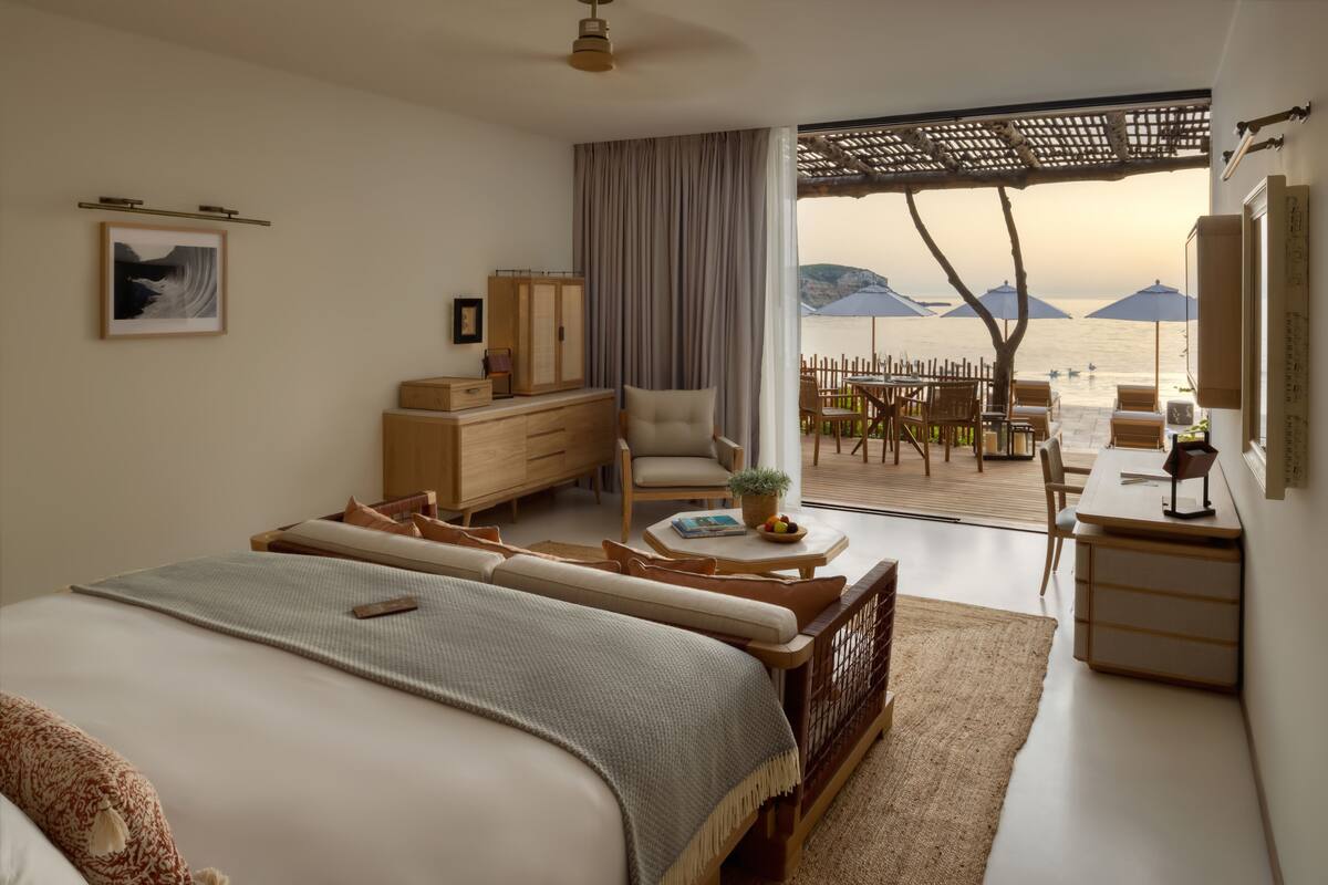 Een slaapkamer met een groot bed, een bureau en uitzicht op het strand.