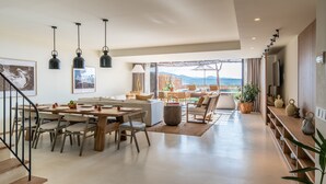A spacious living area with a dining table, chairs, and a sofa. There is a staircase leading to another level. - Six Senses Ibiza (Sant Joan de Labritja)