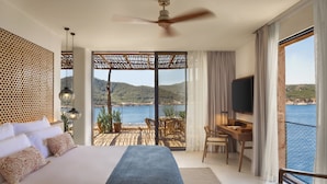 A bedroom with a large bed, a desk, and a view of the sea. - Six Senses Ibiza (Sant Joan de Labritja)