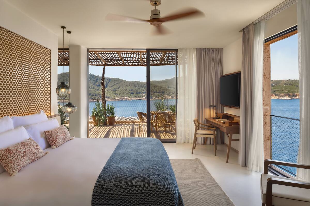 Een slaapkamer met een groot bed, een bureau en uitzicht op zee.