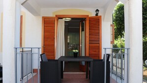 Un patio exterior con una mesa y sillas, vistas del interior y una barandilla.