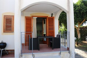 An outdoor patio with a table and chairs, a grill, and an archway leading to a building. - Villa Cavalluccio Marino con piscina idromassaggio (Carini)