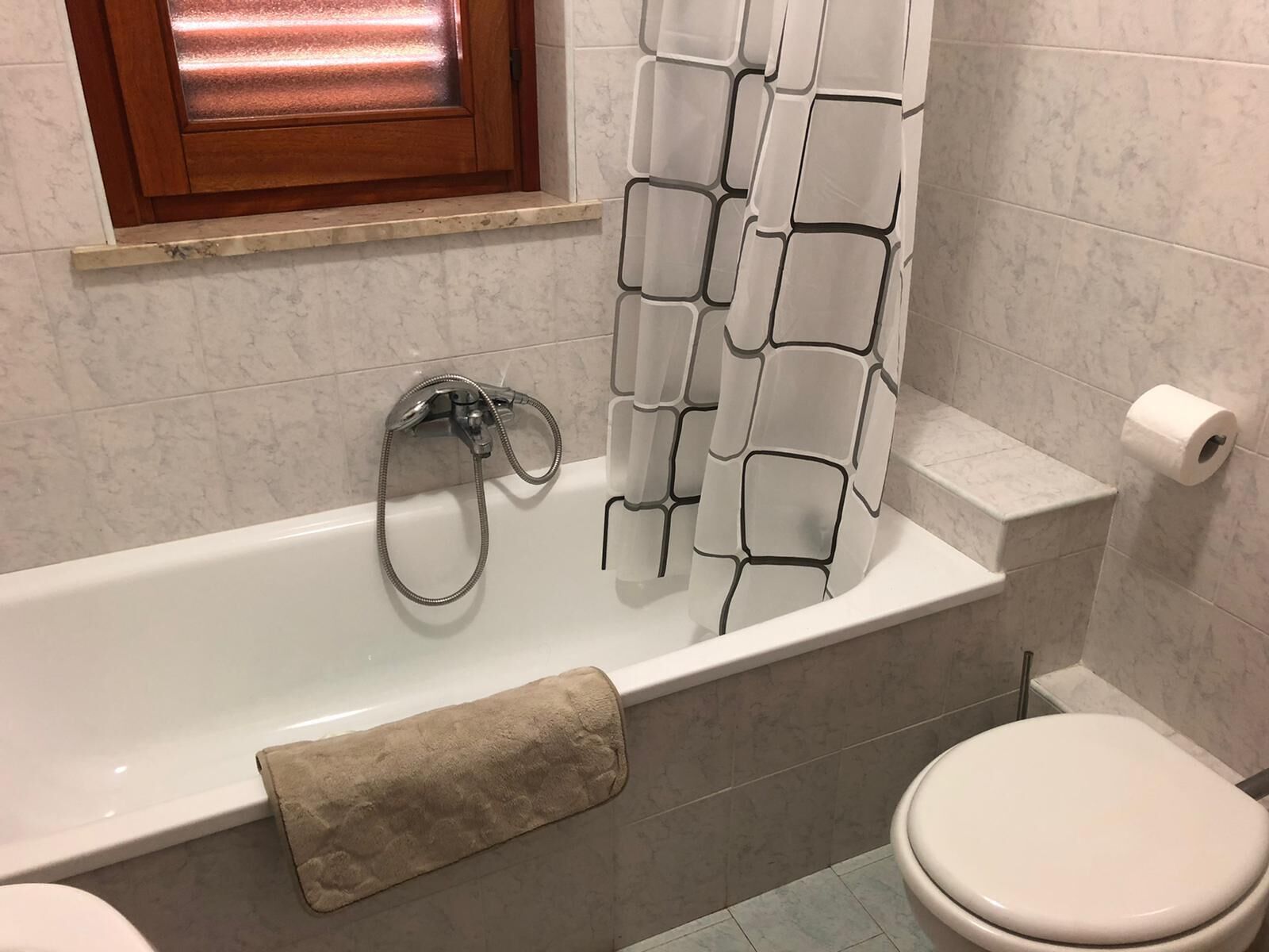 Un baño con bañera, inodoro y toallero.