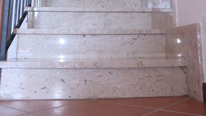 Una escalera de mármol con barandilla de metal que conduce a un piso superior.