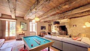 A cozy room with a pool table, a sofa, a fireplace, and a stone wall. - Charme et Tradition (trefumel)