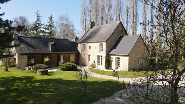 A two-story stone house with a sloped roof, a small front garden, and a gravel driveway. - Charme et Tradition (trefumel)