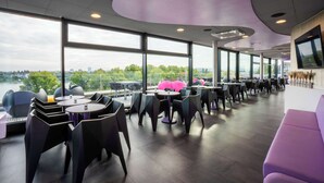 A modern restaurant with large windows offering a view of the city and greenery. - Prize by Radisson, Bonn City (Bonn)