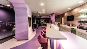 A modern bar area with a curved seating arrangement, a long counter, and a view of the city at night. - Prize by Radisson, Bonn City (Bonn)